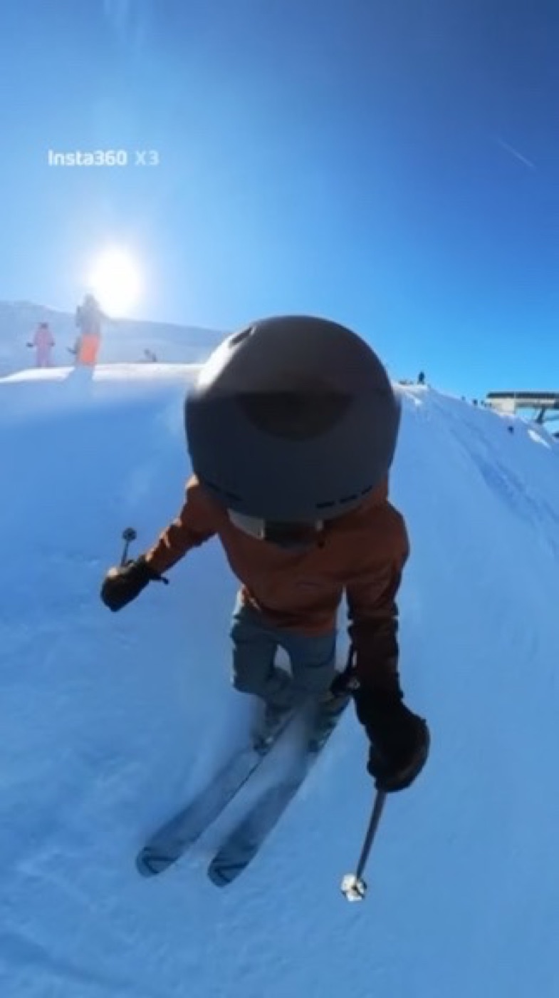 Ribhav skiing down a sunny slope, seen from a helmet-mounted camera